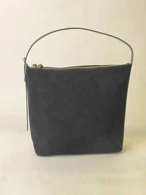un sac à main noir posé sur une table près d'un mur blanc