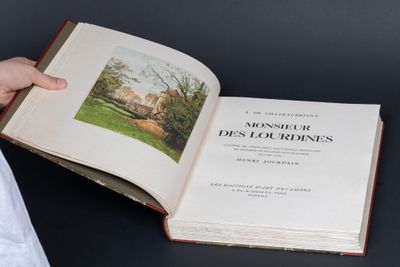 quelqu'un tient un livre dans lequel figure l'image d'une maison