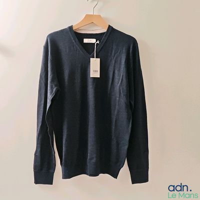 Le pull est suspendu à un cintre accroché au mur.