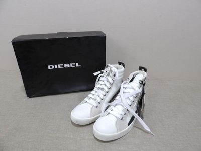 baskets Diesel blanches et noires avec une boîte posée par terre