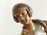 a bronze statue of a woman holding a bird