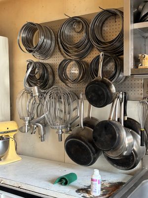 pots and pans are hanging on a wall in a kitchen
