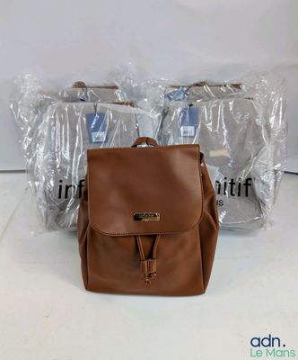brown leather backpack with zippers and clear plastic bags on a white surface