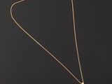 a gold necklace with a flower pendant on a black background