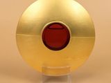 a gold plate with a red button on it