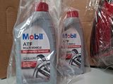 two bottles of mobil are sitting on a counter next to a bag of toilet paper