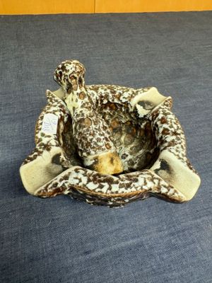 a giraffe statue sitting in a bowl on a bed