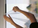 a person that is holding a curtain over a window