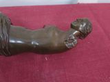 a bronze statue of a man laying on a red cloth
