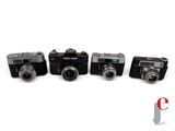 four cameras are lined up in a row on a white surface