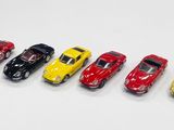 Six petites voitures sont alignées en rang sur une surface blanche.