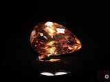 a close up of a large orange diamond on a black surface