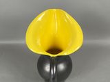 un vase jaune et noir, dont la base est noire, posé sur une surface grise