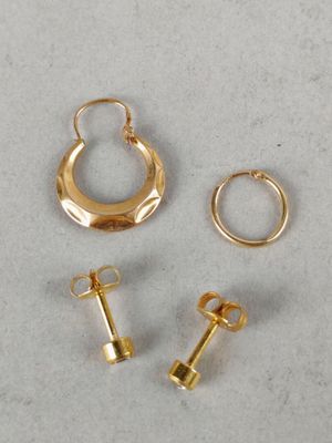 three pairs of gold hoop earrings and a gold earring