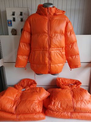 an orange jacket and two pillows are on a white bench