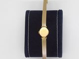 a close up of a gold watch on a blue velvet case