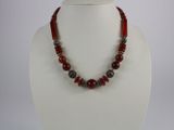 a close up of a necklace with red beads on a mannequin