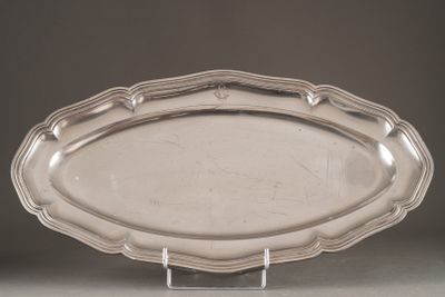 an oval silver platter on a stand on a gray surface