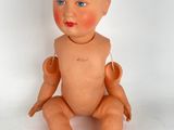 a baby doll sitting on a white surface with blue eyes