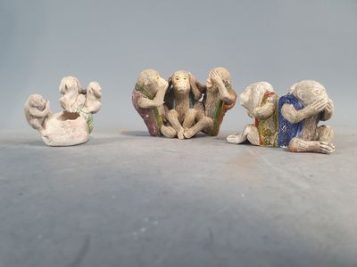trois figurines de singes posées sur une table, sur fond blanc