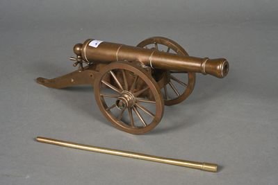 a small brass cannon with a wooden rod next to it