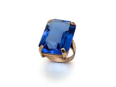 un gros plan d'une bague en pierre bleue posée sur une surface blanche