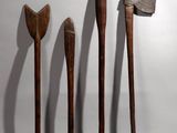 three wooden axes are lined up against a white wall