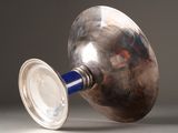 a silver vase with a blue handle sitting on a table