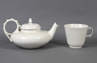 une théière blanche et une tasse posées l'une à côté de l'autre
