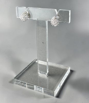clear acrylic jewelry display stand with a pair of earrings on it
