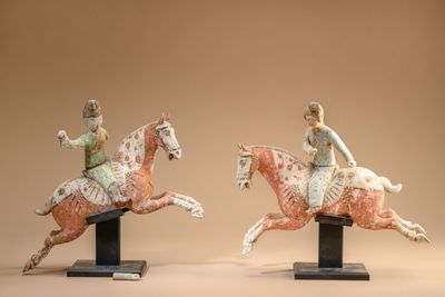 two figurines of a woman riding a horse and a man riding a horse