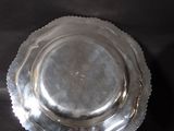 a silver plate with a scalloped edge on a black background