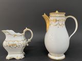 two white and gold vases and a white pitcher on a black background