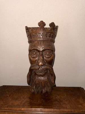 une statue représentant un homme coiffé d'une couronne, posée sur une table en bois