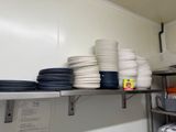 many plates and pans stacked on a shelf in a kitchen