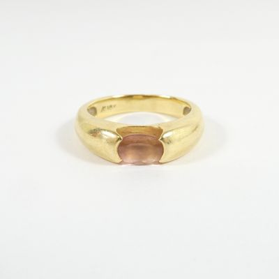 a close up of a gold ring with a pink stone