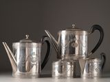 a silver tea set on a table next to cups and a teapot