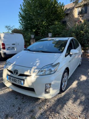 une Toyota Prius blanche garée sur un parking à côté d'une camionnette