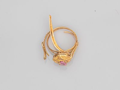 Gros plan sur une bague en or ornée d'une pierre rose