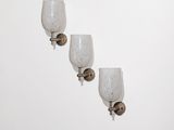 trois appliques murales en verre sur un mur blanc, devant un fond blanc