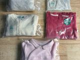 Plusieurs sacs de vêtements sont posés sur une table en bois.