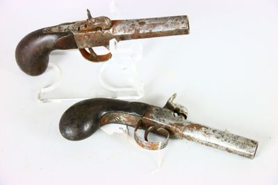une paire de pistolets anciens exposés sur un support blanc