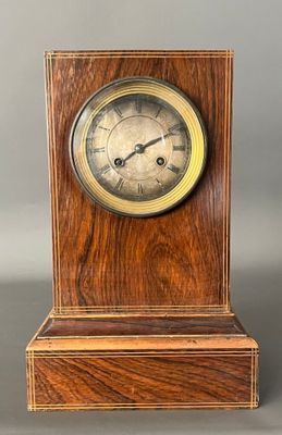 une image représentant une horloge en bois posée sur un socle, sur fond gris