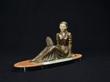 statue d'une femme assise sur une planche de surf sur fond noir