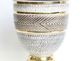 a close up of a silver and gold vase on a white background