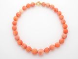 un bracelet en perles couleur corail avec un fermoir doré