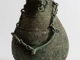 un vase vert entouré d'une chaîne, posé sur une surface blanche