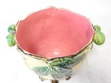 a pink bowl with green leaves on it on a white surface