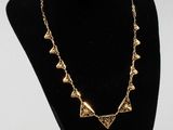a black mannequin with a gold necklace on it