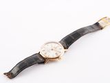 an image of a gold watch with a black leather strap